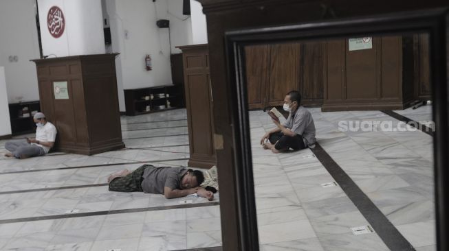 Refleksi umat Islam membaca Al-Quran di Masjid Cut Meutia, Menteng, Jakarta, Jumat (16/4/2021). [Suara.com/Angga Budhiyanto]