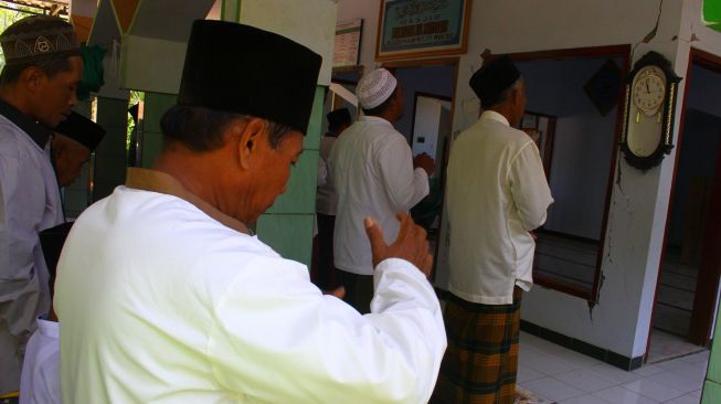 Korban gempa Malang melakukan shalat Jumat di teras dan di jalan depan Masjid Hadiyatul Lil Muttaqin di Jogomulyan, Tirtoyudo, Malang, Jawa Timur, Jumat (16/4/2021). ANTARA FOTO/Ari Bowo Sucipto