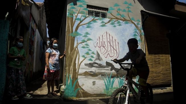 Sejumlah anak bermain di depan mural kaligrafi di Kampung Wisata Budaya Kaligrafi di Bandung, Jawa Barat, Jumat (16/4/2021). ANTARA FOTO/Novrian Arbi