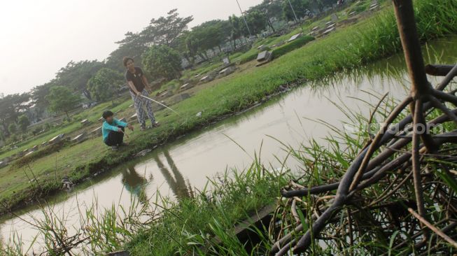 Warga memancing di TPU Tanah Kusir, Jakarta Selatan, Jumat (16/4/2021).  [Suara.com/Dian Latifah]
