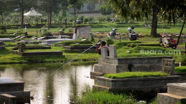 Warga memancing di TPU Tanah Kusir, Jakarta Selatan, Jumat (16/4/2021).  [Suara.com/Dian Latifah]
