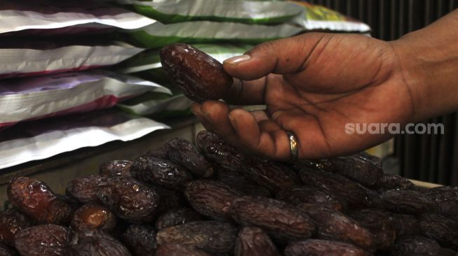 Pedagang menunjukkan buah kurma di kawasan Tanah Abang, Jakarta Pusat, Minggu (18/4/2021). [Suara.com/Dian Latifah]