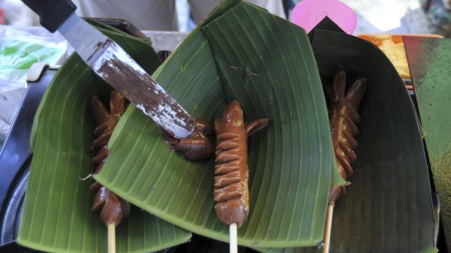 Pelaku usaha menyajikan makanan di atas daun pisang saat kegiatan "Minggu Tanpa Plastik" di Denpasar, Bali, Minggu (18/4/2021). [ANTARA FOTO/Fikri Yusuf]