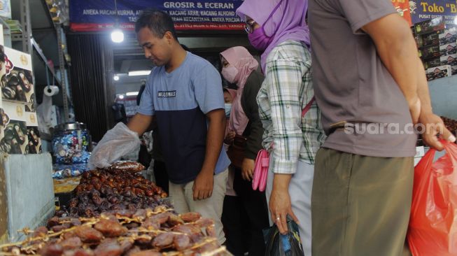 Pedagang melayani pembeli buah kurma di kawasan Tanah Abang, Jakarta Pusat, Minggu (18/4/2021). [Suara.com/Dian Latifah]