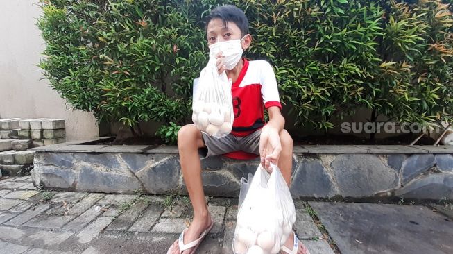 Angga Purnama Alamsyah, remaja 15 tahun yang masih duduk di bangku sekolah Kelas 8 SMP, menjajakan telur ayam kampung di depan sebuah restoran di Alam Sutera, Tangerang Selatan (Tangsel), Sabtu (17/4/2021). [SuaraJakarta.id/Wivy Hikmatullah]