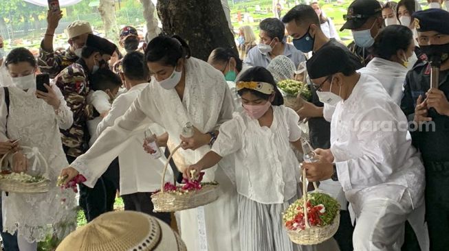 Aktris Dian Sastrowardoyo bersama keluarga menabur bunga di pusara ayah mertuanya, Adiguna Sutowo di Tempat Pemakaman Umum (TPU) Tanah Kusir, Jakarta, Minggu (18/4/2021). [Suara.com/Evi Ariska]