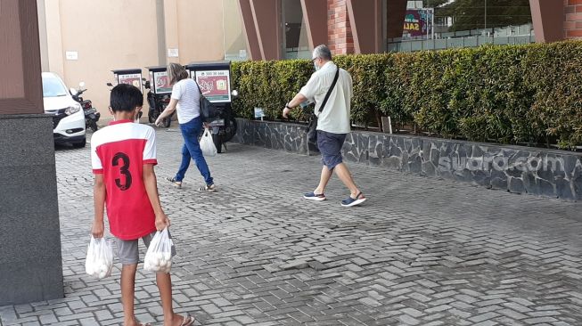 Angga Purnama Alamsyah, remaja 15 tahun yang masih duduk di bangku sekolah Kelas 8 SMP, menjajakan telur ayam kampung di depan sebuah restoran di Alam Sutera, Tangerang Selatan (Tangsel), Sabtu (17/4/2021). [SuaraJakarta.id/Wivy Hikmatullah]