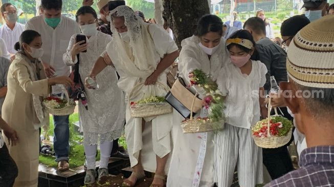 Aktris Dian Sastrowardoyo bersama keluarga menabur bunga di pusara ayah mertuanya, Adiguna Sutowo di Tempat Pemakaman Umum (TPU) Tanah Kusir, Jakarta, Minggu (18/4/2021). [Suara.com/Evi Ariska]