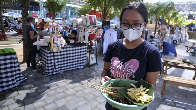 Pelaku usaha menyajikan makanan di atas daun pisang saat kegiatan "Minggu Tanpa Plastik" di Denpasar, Bali, Minggu (18/4/2021). [ANTARA FOTO/Fikri Yusuf]