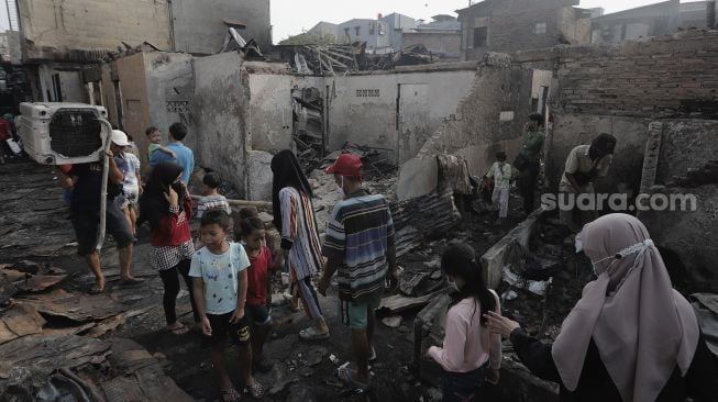 Warga mengevakuasi barang dari sisa-sisa permukiman yang terbakar di Keagungan, Taman Sari, Jakarta Barat, Senin (19/4/2021). [Suara.com/Angga Budhiyanto]