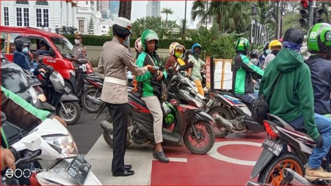 Personel Polisi Wanita (Polwan) Memberikan Masker Kepada Pengemudi Ojek Online. [Ist]