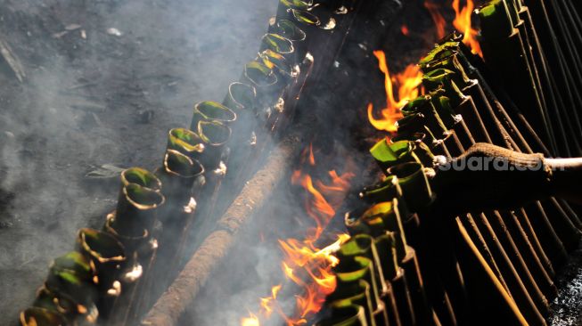 Pembuat merapihkan nasi lemang yang sedang dibakar, di kawasan Senen, Jakarta Pusat, Senin (19/4/2021). [Suara.com/Dian Latifah]