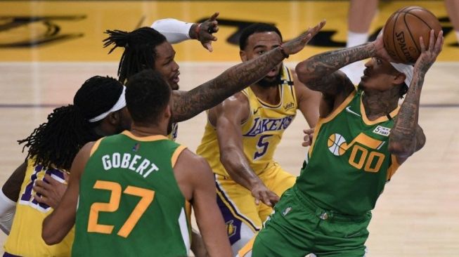 Pemain Utah Jazz Jordan Clarkson berusaha memasukkan bola di bawah hadangan dua pemain Los Angeles Lakers Talen Horton-Tucker dan Ben McLemore dalam laga NBA di Staples Center, Los Angeles, California, 19 April 2021. (Getty Images via AFP/HARRY HOW)