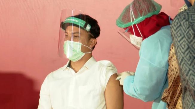 Aktor Nicholas Saputra melakukan vaksinasi Covid-19 di Galeri Nasional Indonesia, Senin (19/4/2021). [Tangkapan Layar YouTube Setkab]