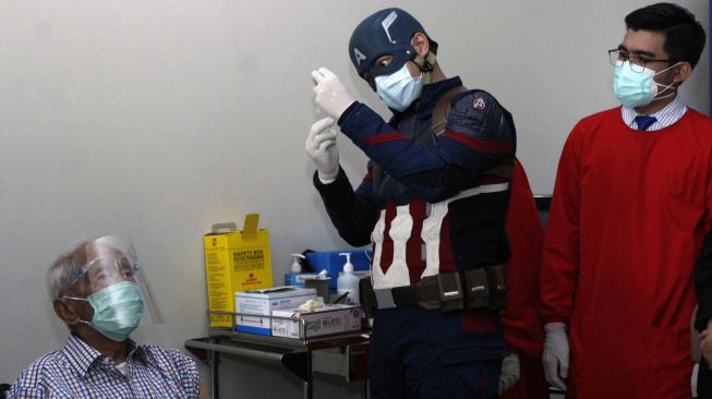 Dokter superhero Rollando Erric Manibuy bersiap menyuntikkan vaksin COVID-19 dosis kedua kepada lansia berusia 104 tahun Wirjawan Hardjamulia di Rumah Sakit Vania, Kota Bogor, Jawa Barat, Selasa (20/4/2021).  ANTARA FOTO/Arif Firmansyah