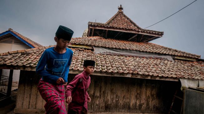 Anak berjalan melintasi Masjid Kuno Baitul Arsy, Pandeglang, Banten, Senin (19/4/2021). ANTARA FOTO/Muhammad Bagus Khoirunas