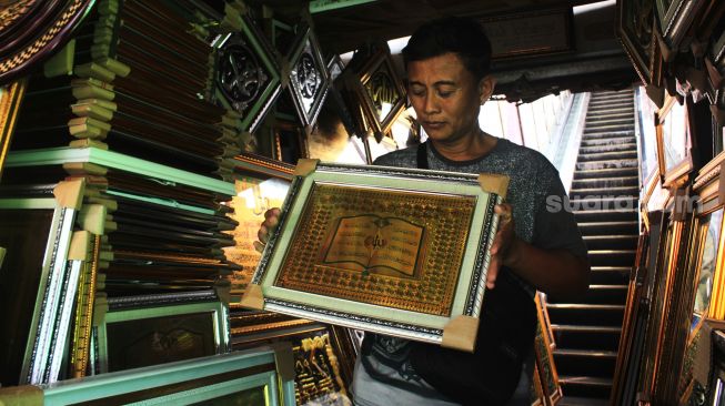 Aktivitas penjual kaligrafi di Pasar Baru, Jakarta, Senin (19/4/2021). [Suara.com/Dian Latifah]
