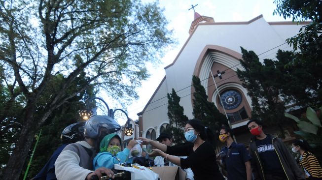 Sejumlah umat Katolik membagikan makanan untuk berbuka puasa (takjil) kepada pengendara kendaraan di depan Gereja Katolik Santo Paulus Miki, Salatiga, Jawa Tengah, Rabu (21/4/2021).  ANTARA FOTO/Aloysius Jarot Nugroho