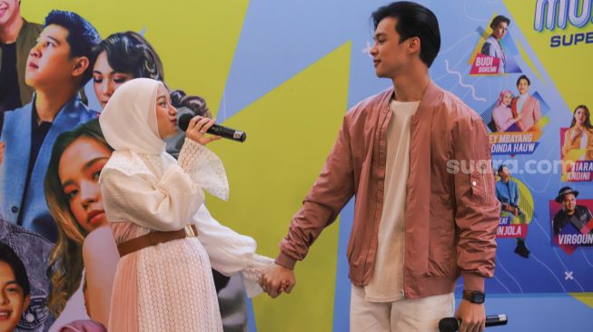 Kemesraan pasangan Rey Mbayang dan Dinda Hauw bernyanyi membawakan lagu 'Kuyakin Bahagia' saat acara perilisan CD Kompilasi 'Musikini Superhits 2' di Kawasan Kemang, Jakarta Selatan, Rabu (21/4/2021). [Suara.com/Alfian Winanto]