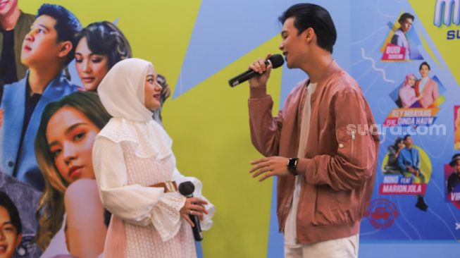 Pasangan Rey Mbayang dan Dinda Hauw bernyanyi membawakan lagu 'Kuyakin Bahagia' saat acara perilisan CD Kompilasi 'Musikini Superhits 2' di Kawasan Kemang, Jakarta Selatan, Rabu (21/4/2021). [Suara.com/Alfian Winanto]