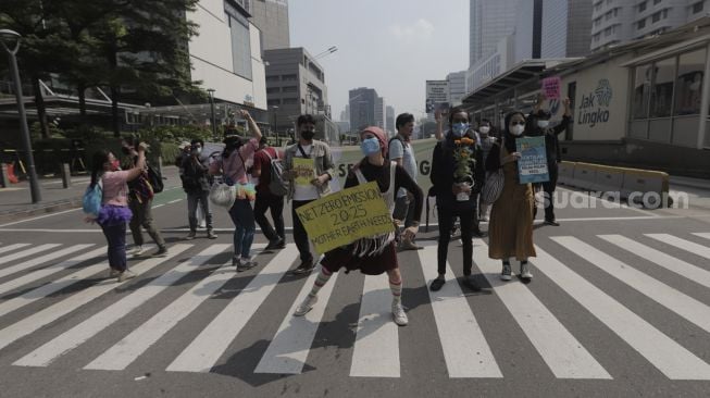 Aktivis lingkungan hidup menari saat menggelar aksi "Joget Jagat" di Jalan MH Thamrin, Jakarta, Kamis (22/4/2021). [Suara.com/Angga Budhiyanto]