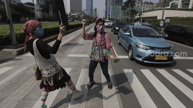 Aktivis lingkungan hidup menari saat menggelar aksi "Joget Jagat" di Jalan MH Thamrin, Jakarta, Kamis (22/4/2021). [Suara.com/Angga Budhiyanto]