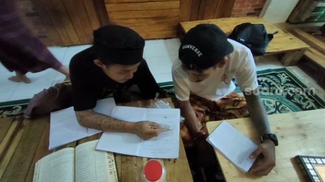 Sejumlah anak punk jalanan tengah mempelajari Al-Quran di Pesantren Tasawuf Underground di Ruko Cimanggis Ciputat, Kota Tangerang Selatan (Tangsel). [SuaraJakarta.id/Wivy Hikmatullah]