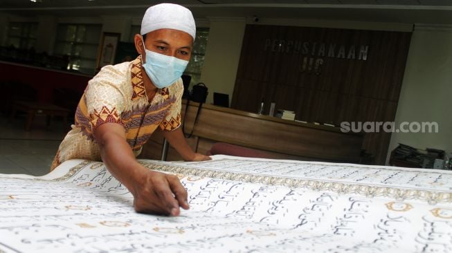 Petugas menunjukan Al-quran besar di Perpustakaan Jakarta Islamic Centre (JIC), Jakarta Utara, Kamis (22/4/2021).  [Suara.com/Dian Latifah]

