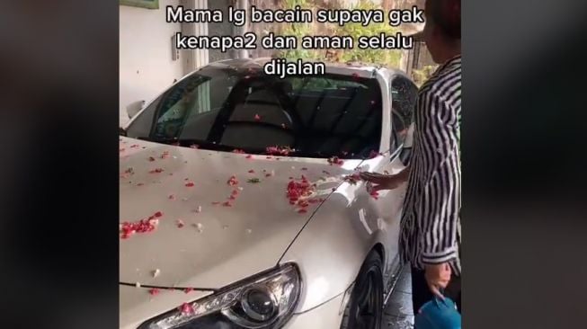 Sebuah mobil dimandikan air kembang oleh pemilik. katanya biar selamat (TikTok)