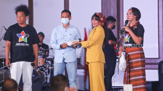 Penyanyi Nowela Auparay (kedua kanan) memberikan barangnya berupa tas yang dilelang untuk membantu korban bencana alam di Nusa Tenggara Timur saat konser amal Suara Nusa Timur di Pasar Minggu, Jakarta Selatan, Sabtu (24/4/2021). [Suara.com/Alfian Winanto]