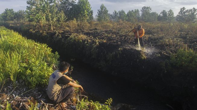 Petugas Badan Penanggulangan Bencana Daerah (BPBD) melakukan proses pendinginan lahan gambut. lahan. di Ogan Ilir terbakar (24/4/2021). [ANTARA FOTO/Makna Zaezar]