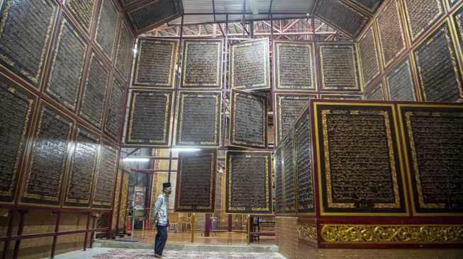 Pengunjung membaca ayat-ayat yang ada di Al Quran Al-Akbar di Palembang, Sumatera Selatan, Jumat (23/4/2021).  ANTARA FOTO/Nova Wahyudi