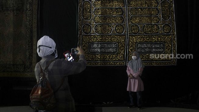 Pengunjung berfoto di depan salah satu koleksi dalam Pameran Artefak Nabi Muhammad SAW di Jakarta Islamic Center, Koja, Jakarta, Minggu (25/4/2021). [Suara.com/Dian Latifah]