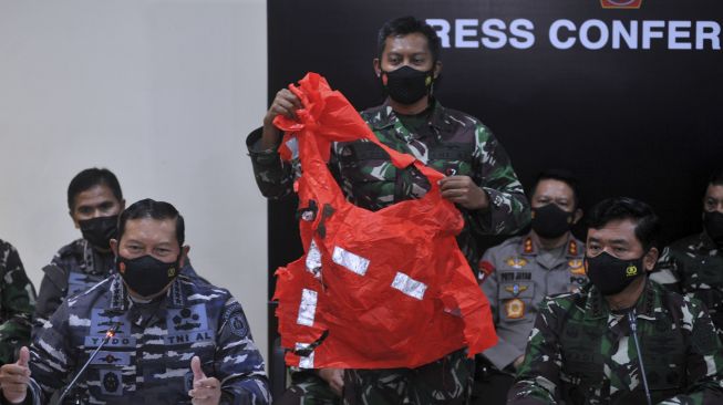 Panglima TNI Marsekal TNI Hadi Tjahjanto (kanan) dan Kepala Staf Angkatan Laut Laksamana TNI Yudo Margono (kiri) menunjukkan baju keselamatan awak kapal KRI Nanggala 402 yang ditemukan saat konferensi pers di Lanud I Gusti Ngurah Rai, Badung, Bali, Minggu (25/4/2021). [ANTARA FOTO/Fikri Yusuf]