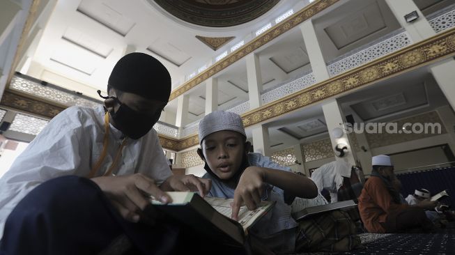 Santri membaca Al-Quran saat mengikuti kegiatan Pesantren Kilat yang diselenggarakan pengurus Masjid An-Nur, Mampang Prapatan, Jakarta, Minggu (25/4/2021). [Suara.com/Angga Budhiyanto]