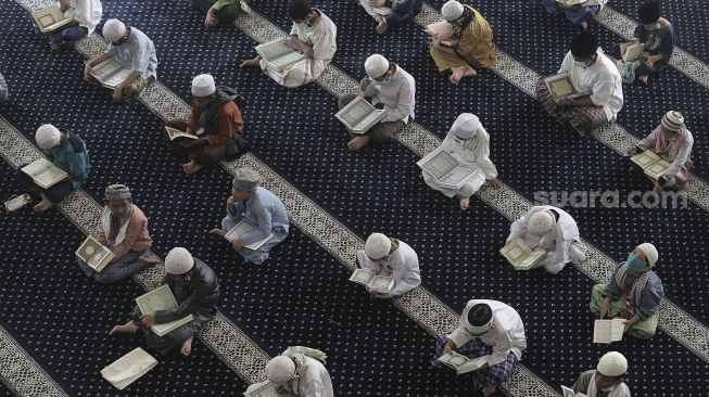 Santri membaca Al-Quran saat mengikuti kegiatan Pesantren Kilat yang diselenggarakan pengurus Masjid An-Nur, Mampang Prapatan, Jakarta, Minggu (25/4/2021). [Suara.com/Angga Budhiyanto]