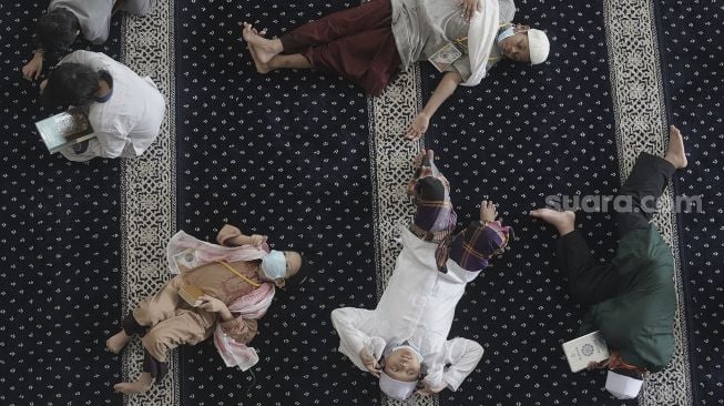 Santri beristirahat di sela-sela mengikuti kegiatan Pesantren Kilat yang diselenggarakan pengurus Masjid An-Nur, Mampang Prapatan, Jakarta, Minggu (25/4/2021). [Suara.com/Angga Budhiyanto]