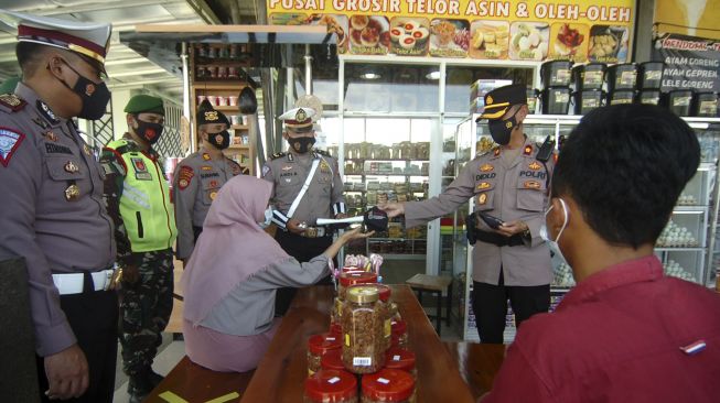 Personel kepolisian memeriksa penerapan protokol kesehatan saat pengetatan dan pengamanan mudik di rest area KM 275, Penarukan, Kabupaten Tegal, Jawa Tengah, Senin (26/4/2021).[ANTARA FOTO/Oky Lukmansyah]