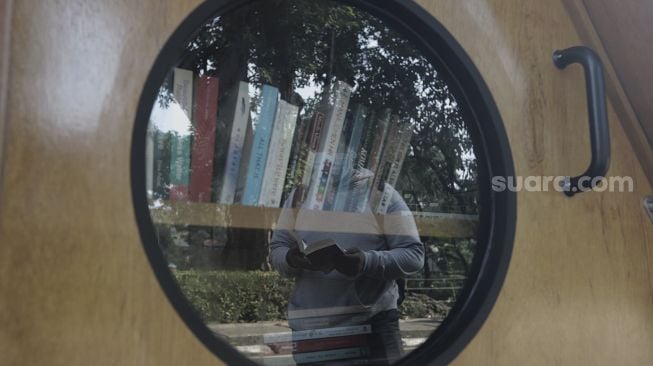 Refleksi warga membaca buku di perpustakaan bersama Bookhive Jakarta di kawasan Taman Situ Lembang, Jakarta, Selasa (27/4/2021). [Suara.com/Angga Budhiyanto]