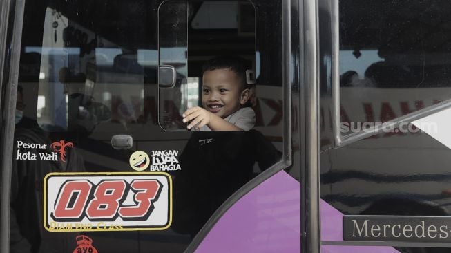 Seorang anak berada di dalam bus di Terminal Pulo Gebang, Jakarta Timur, Selasa bus di Terminal Pulo Gebang, Jakarta Timur, Selasa (27/4/2021). [Suara.com/Angga Budhiyanto]