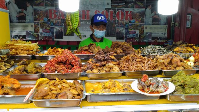 Pedagang nasi kapau menunggu pembeli di Food Street Kramat di Kawasan Senen, Jakarta Pusat, Selasa (27/4/2021). [Suara.com/Alfian Winanto]