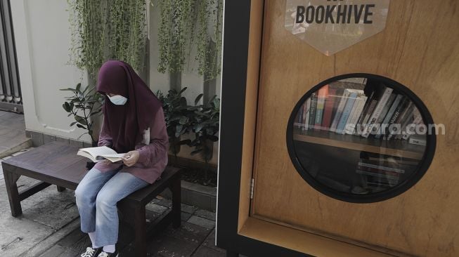 Warga membaca buku di perpustakaan bersama Bookhive Jakarta di kawasan Taman Situ Lembang, Jakarta, Selasa (27/4/2021). [Suara.com/Angga Budhiyanto]