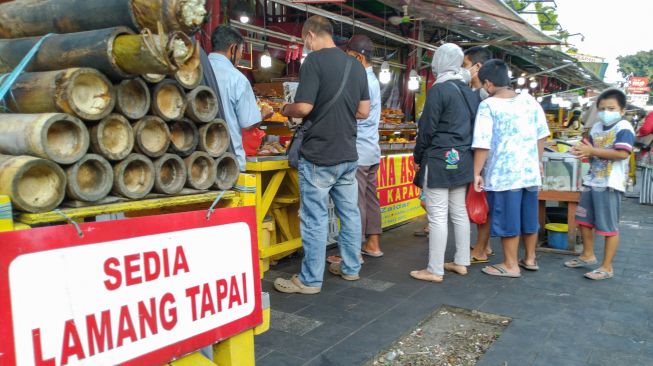 Warga mengantri untuk membeli makanan berbuka puasa di Food Street Kramat di Kawasan Senen, Jakarta Pusat, Selasa (27/4/2021). [Suara.com/Alfian Winanto]