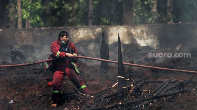 Petugas menarik selang  dii Kawasan Desa Bojong Nangka, Gunung Putri, Bogor, Selasa (27/4/2021). [Suara.com/Dian Latifah]