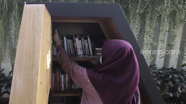 Warga memilih koleksi buku di perpustakaan bersama Bookhive Jakarta di kawasan Taman Situ Lembang, Jakarta, Selasa (27/4/2021). [Suara.com/Angga Budhiyanto]