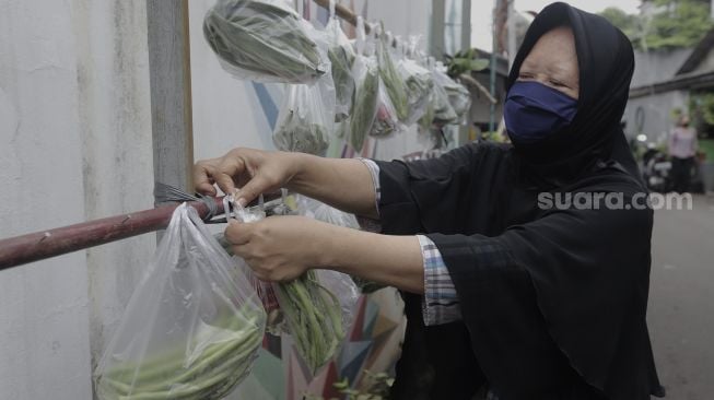 Warga memilah sayuran yang dijajakan secara gratis di Jalan Jati Padang VI RT 002 RW 004, Pasar Minggu, Jakarta Selatan, Rabu (28/4/2021). [Suara.com/Angga Budhiyanto]