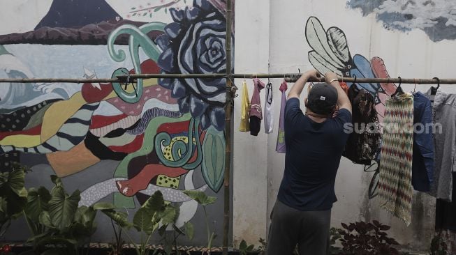 Warga memilih pakaian bekas layak pakai yang dijajakan secara gratis di Jalan Jati Padang VI RT 002 RW 004, Pasar Minggu, Jakarta Selatan, Rabu (28/4/2021). [Suara.com/Angga Budhiyanto]