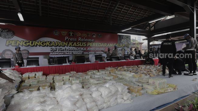 Sejumlah polisi berdiri di dekat barang bukti sabu saat gelar kasus jaringan internasional di Lapangan Bhayangkara Mabes Polri, Jakarta, Rabu (28/4/2021). [Suara.com/Angga Budhiyanto]