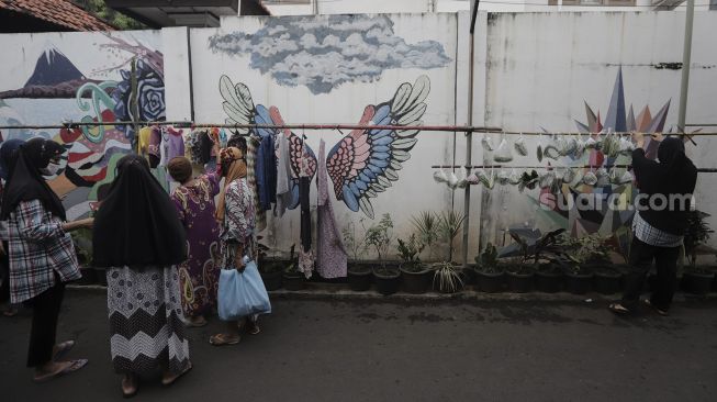 Warga memilah sayuran dan pakaian bekas layak pakai yang dijajakan secara gratis di Jalan Jati Padang VI RT 002 RW 004, Pasar Minggu, Jakarta Selatan, Rabu (28/4/2021). [Suara.com/Angga Budhiyanto]