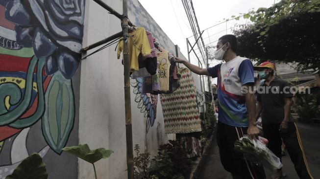 Warga memilih pakaian bekas layak pakai yang dijajakan secara gratis di Jalan Jati Padang VI RT 002 RW 004, Pasar Minggu, Jakarta Selatan, Rabu (28/4/2021). [Suara.com/Angga Budhiyanto]